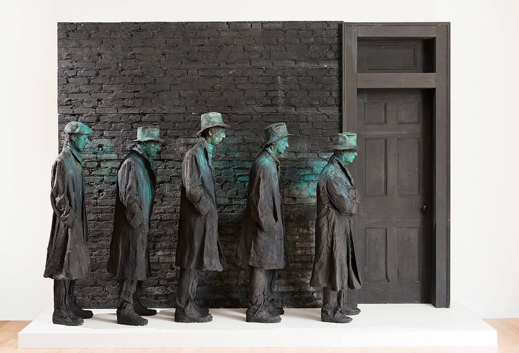 A sculpture of five men wearing coats and hats standing in a 