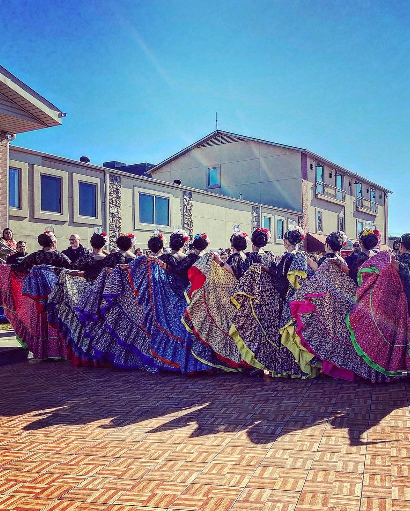 a line of women dressed in brightly colored dresses for Dia de los Muertos