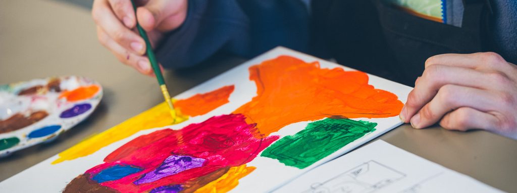 Person painting on canvas with vibrant colors, palette nearby.