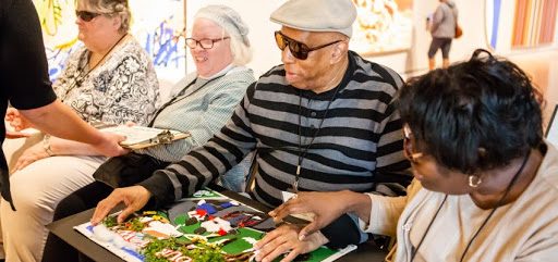 People gathered indoors at a table, focused on a collaborative art project.