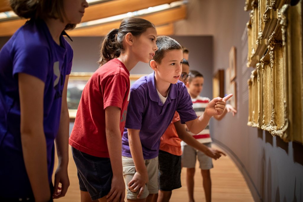 a group of elementary and middle school students look at Martin Johnson Heade's Gems of Brazil paintings in the early american art gallery