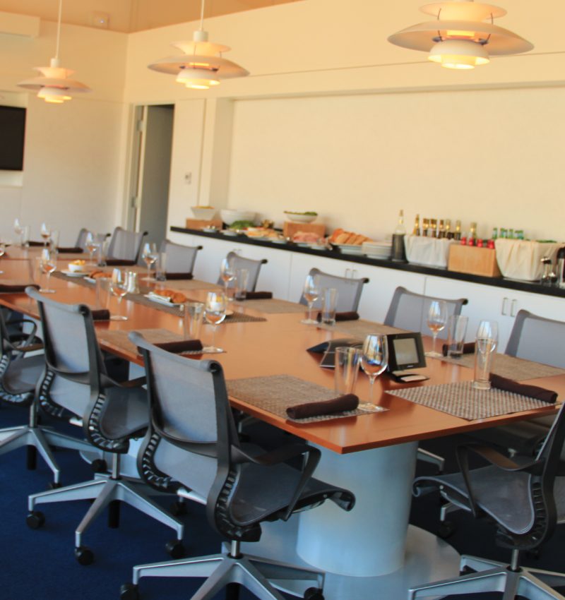 Modern conference room with a long table, office chairs, and a sideboard with food and drinks.