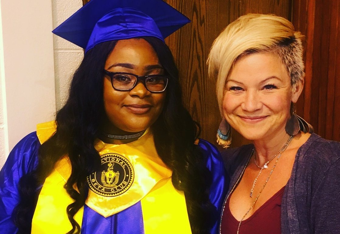 Two people posing; one in a blue graduation outfit with a National Beta Club stole.