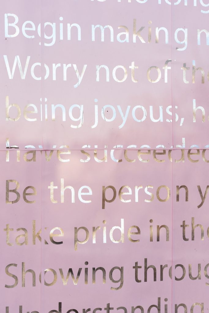 Gold text printed on pink paper, showing part of a letter featured in the Dear Friend exhibition. The words 