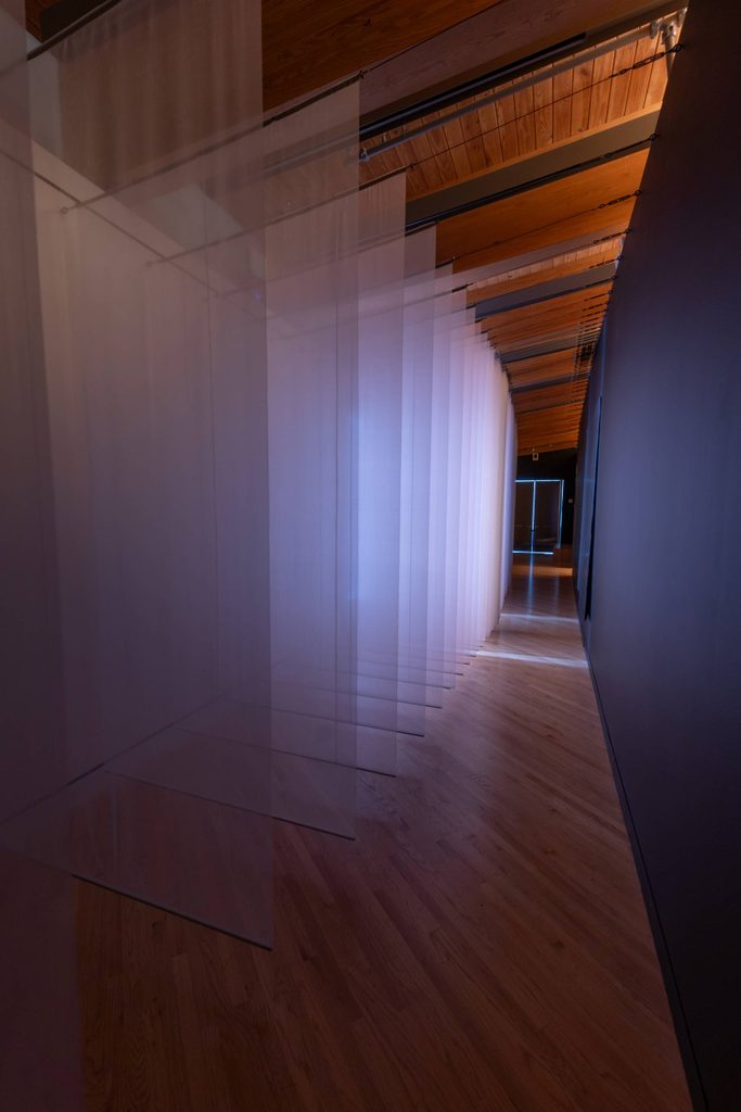 row of fabric banners hanging from wall with soft light shinning through