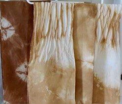 multiple dyed fabrics in shades of beige and brown hanging on hangers