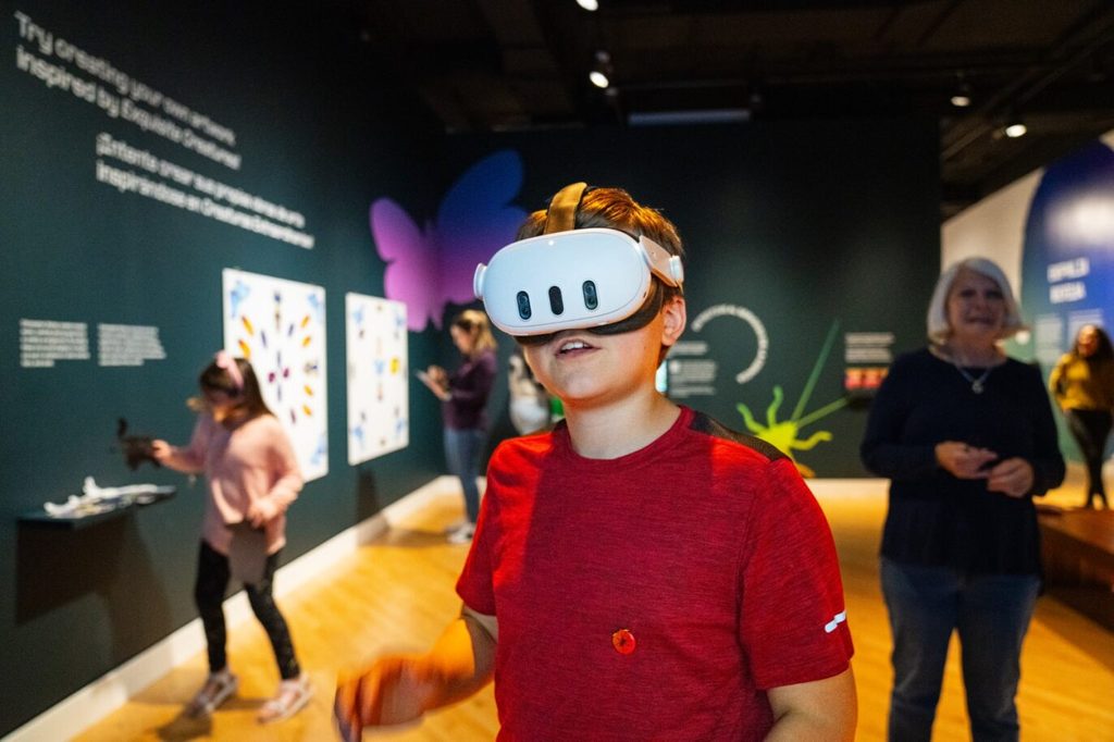 Boy experiencing Exquisite Creatures exhibit using a VR headset.