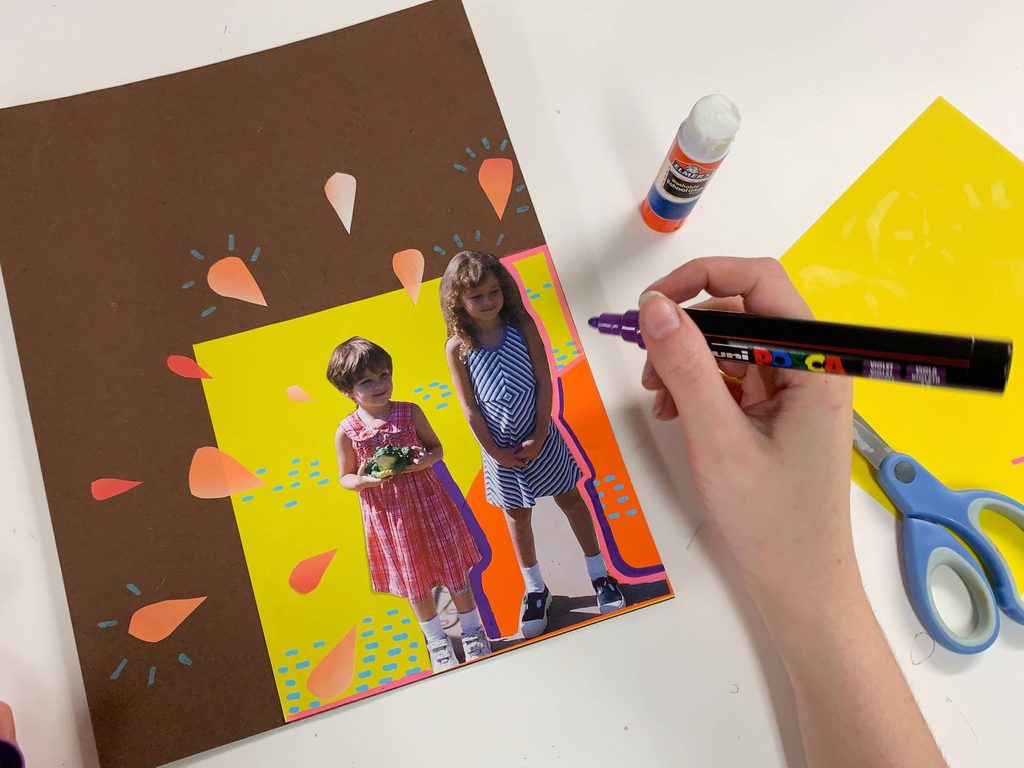 a pair of hands decorating a piece of paper decorated with orange teardrops and a photo of two young girls with a marker