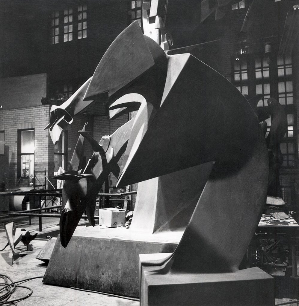 a black and white photograph of a rusted steel abstract sculpture