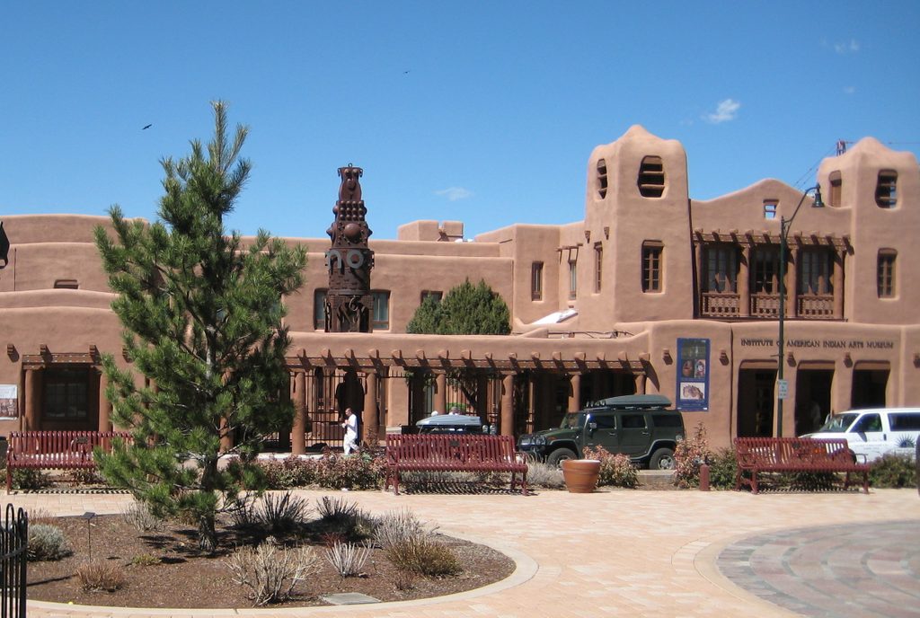 the exterior entrance to the institute of american indian arts in new mexico set against a clear blue sky