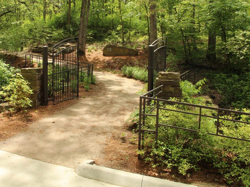 Intersection of paved trails with one leading into forest