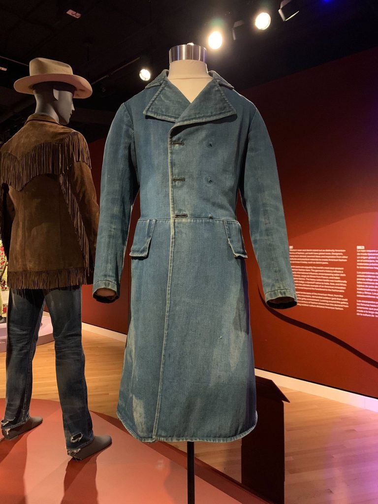 a denim frock coat from the 1850s on a mannequin in a gallery space