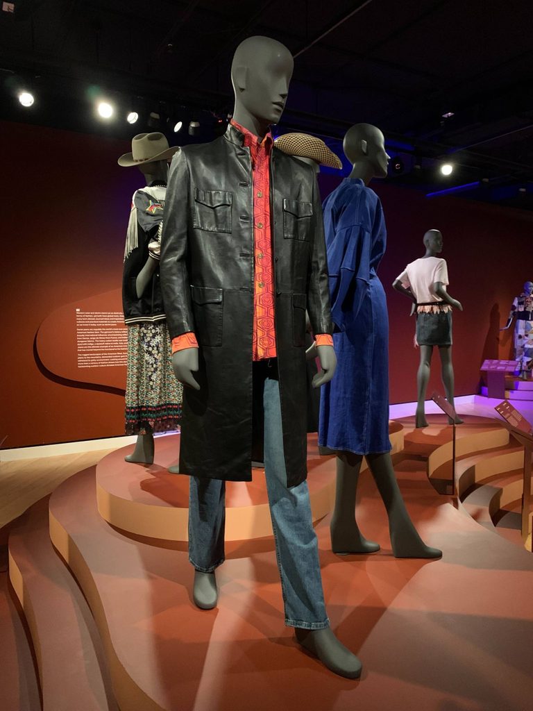 a bright red-orange shirt and black leather jacket on a mannequin in a gallery space