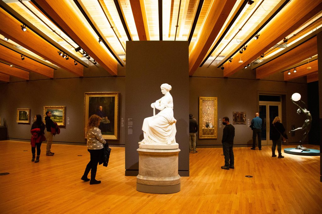 several people viewing artwork in the crystal bridges gallery, the center featuring a white sculpture of Sappho on a marble pedestal