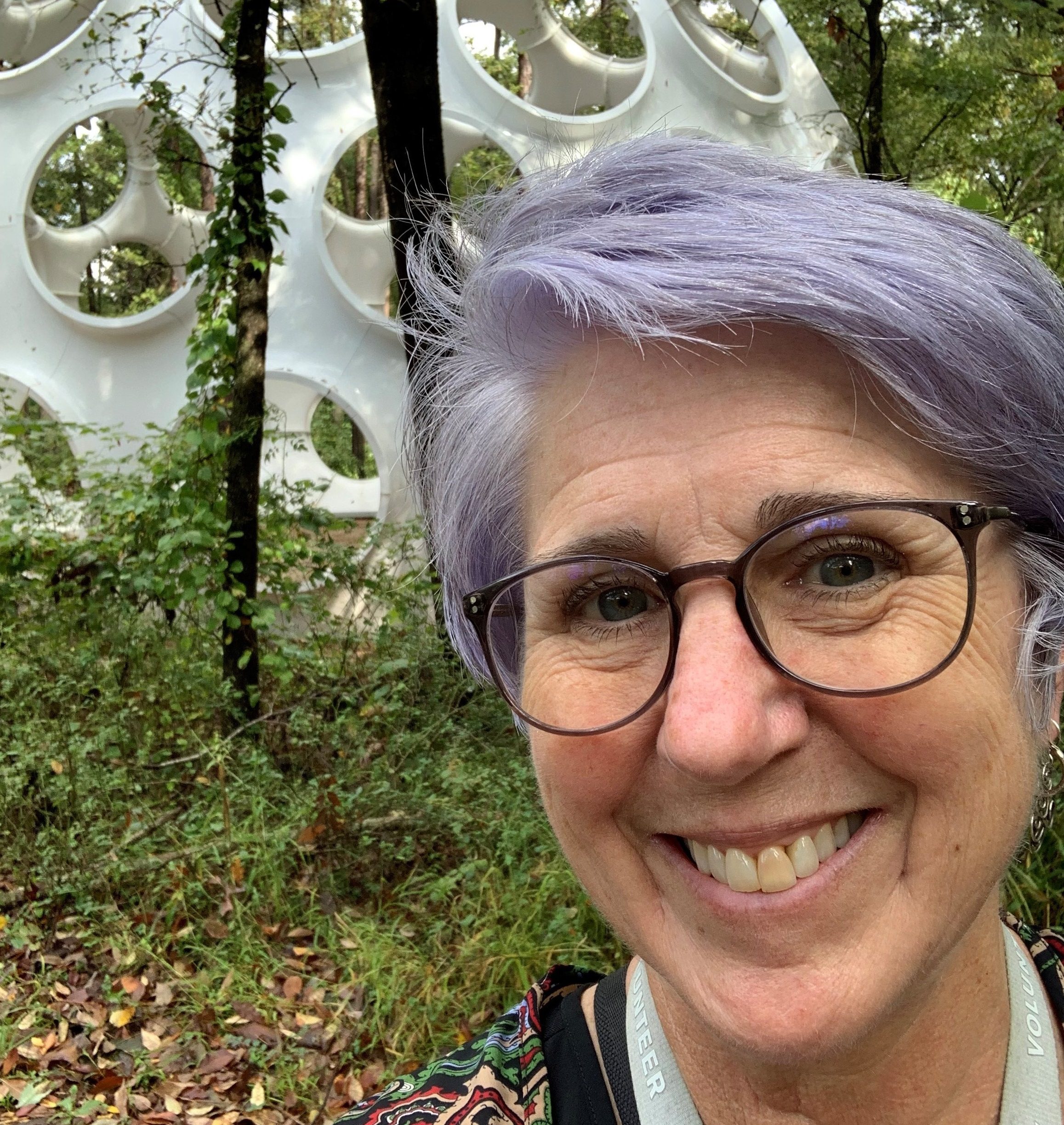 image of volunteer janet cherry in front of the fly's eye dome on the trails