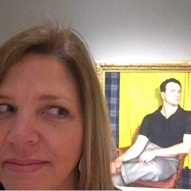 staff member poses with portrait of bob in the gallery