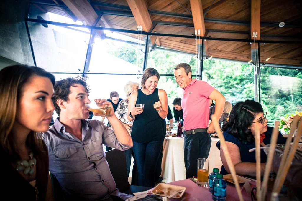 two guests laugh in eleven surrounded by people at a culinary event