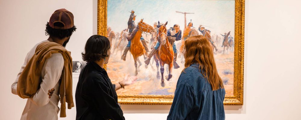 Three people view a work in 'Knowing the West' at Crystal Bridges.