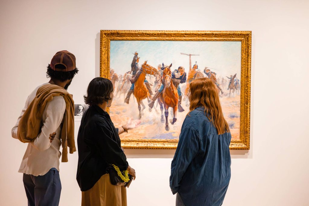 Three people looking at artworks in Knowing the West