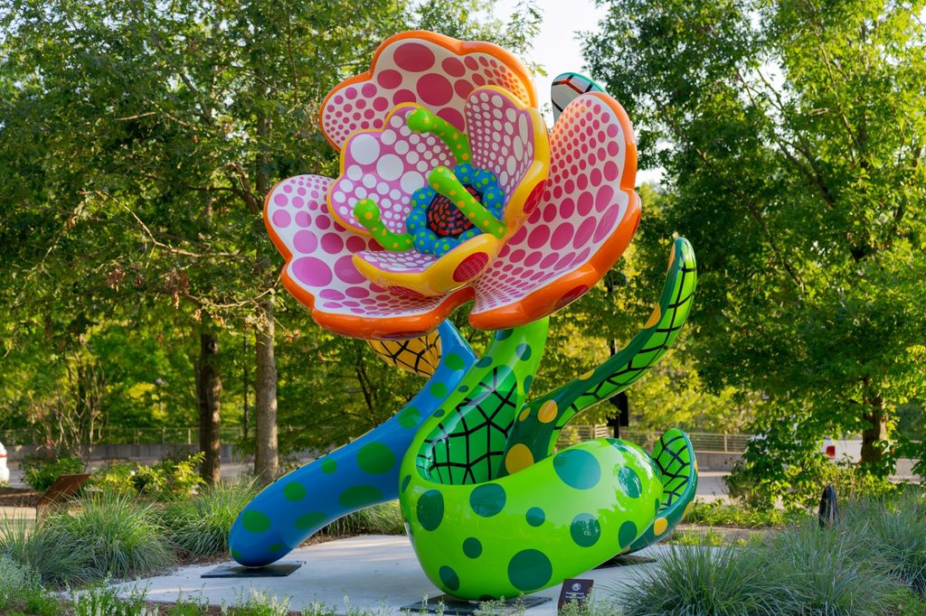 Una gran flor de colores hecha de acero pintado posa como una serpiente enfurecida en el Sendero del Huerto en Crystal Bridges.
