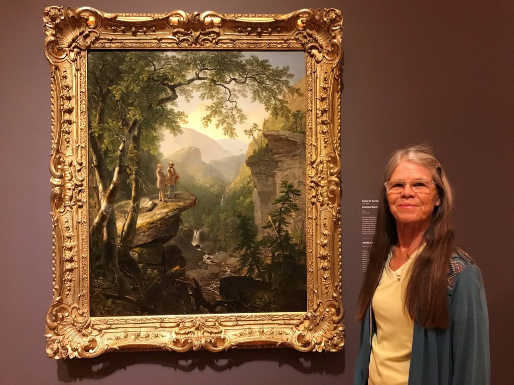 a volunteer poses with Kindred Spirits painting