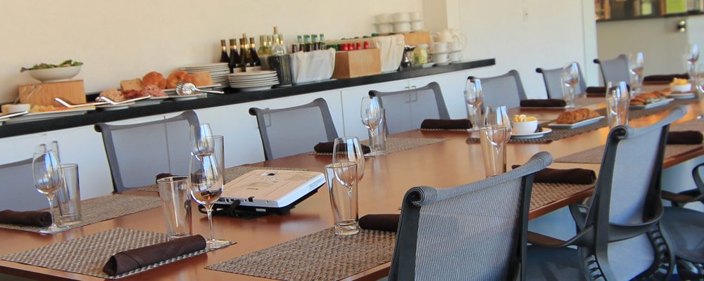 Conference room with a long table, ergonomic chairs, and a buffet with food and beverages.