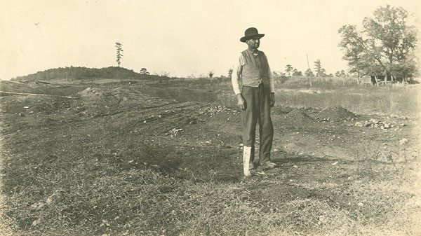 Unidentified man points to the spot where the first diamond in Arkansas was found, near Murfreesboro (Pike County); circa 1920.