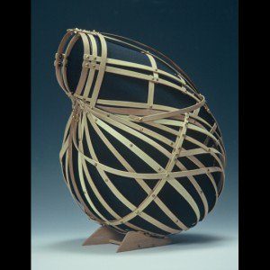 Interwoven wooden slats form a rounded, basket-like sculpture on a small base.