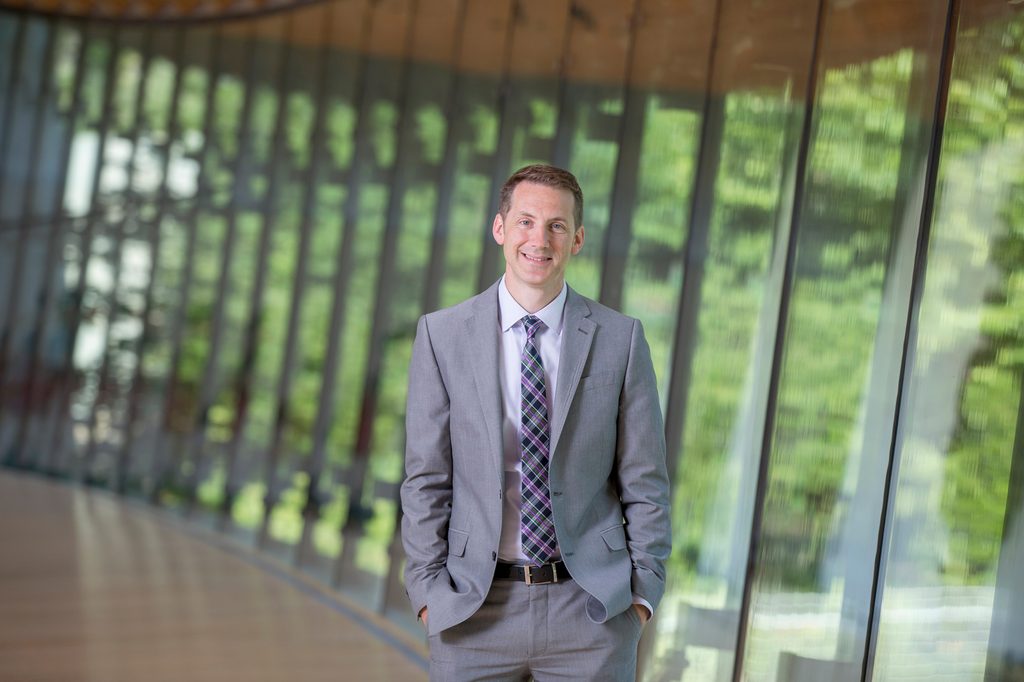 Man in suit stands facing the camera