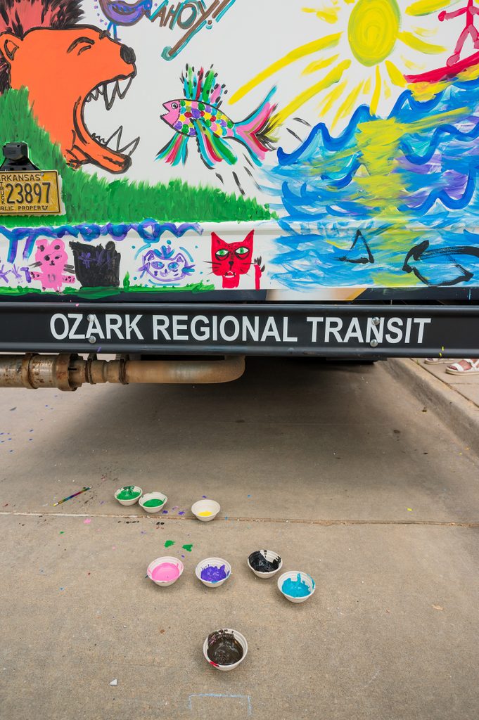 Community event in fayetteville with people painting on a bus