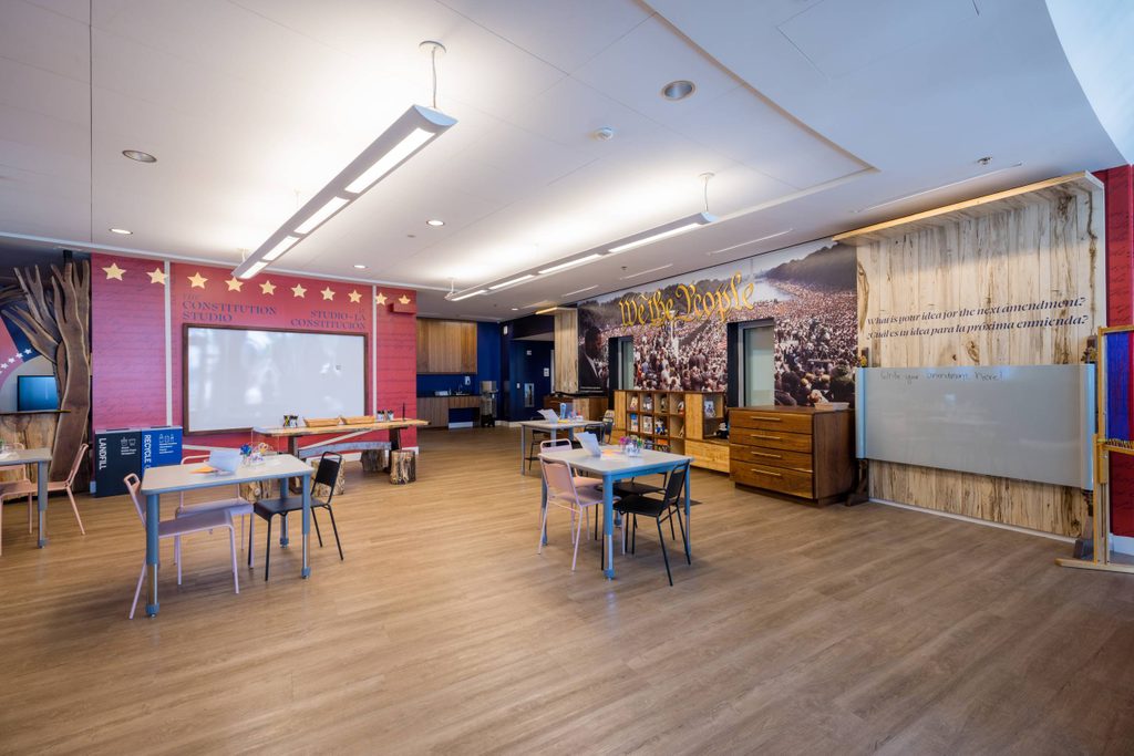an artmaking space at Crystal Bridges with tables and designs on the walls inspired by the we the people exhibition