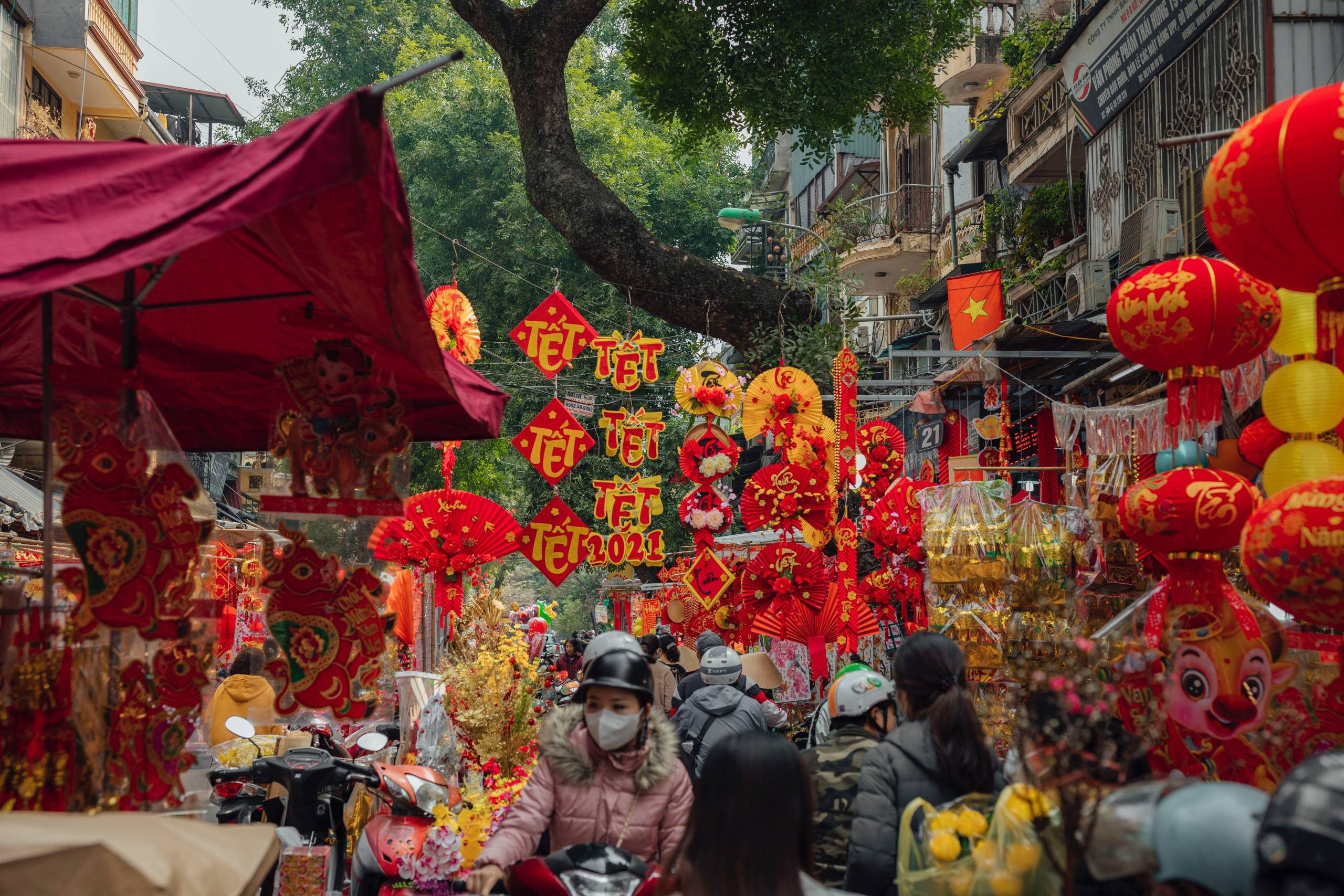 a vietnam street decorated with red and yellow streamers, banners, and lanterns during Tet