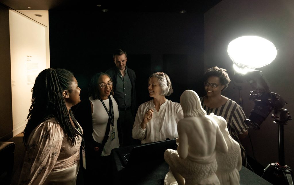 A group of scholars gathers around a sculpture in the Black Box at Crystal Bridges Museum of American Art.