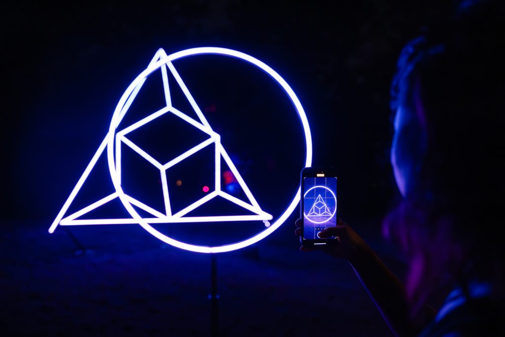 A guest takes a picture of Klip Collective's Exploded Light Sculpture with their phone
