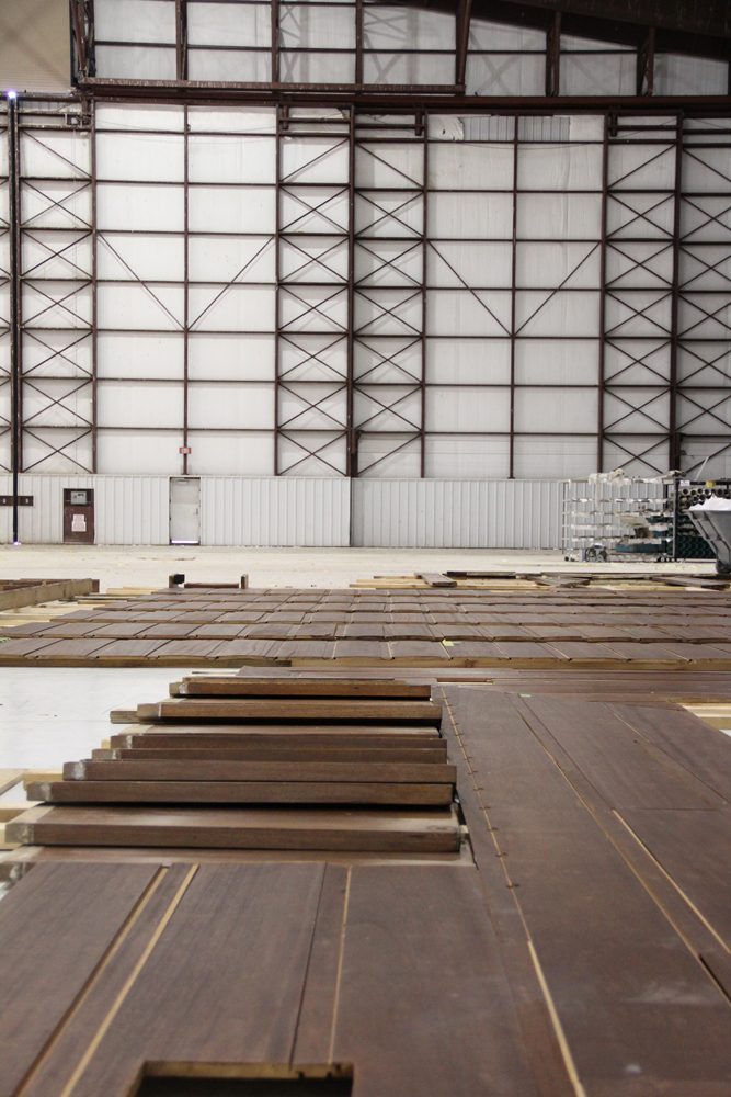 Industrial interior with grid-patterned wall and wooden planks laid on the floor.