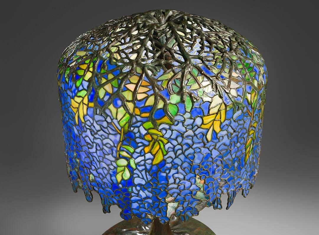 a stained glass desk lamp with blue, purple, green, and yellow colors designed to look like a wisteria tree