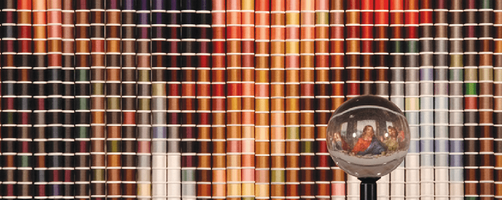Colorful thread grid with glass sphere reflecting an image.